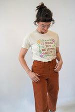 Person wearing a white t-shirt with text and graphics, standing against a plain background