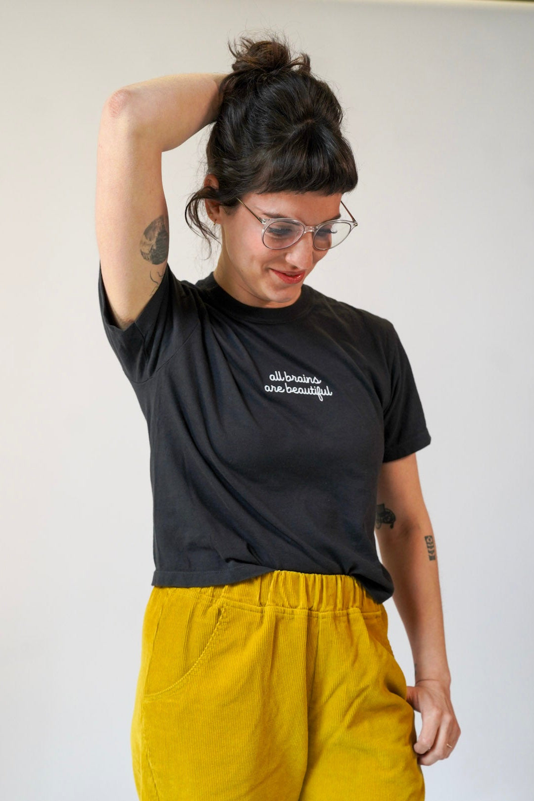 Person wearing a black t-shirt with text and yellow pants against a white background