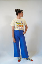 Person wearing a colorful graphic t-shirt and blue pants on a white background