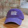 Purple cap with text on a wooden surface with a brick wall background