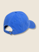 A blue cotton baseball cap shown from the back, featuring an adjustable strap with a gold-tone metal buckle, set against a solid beige background.