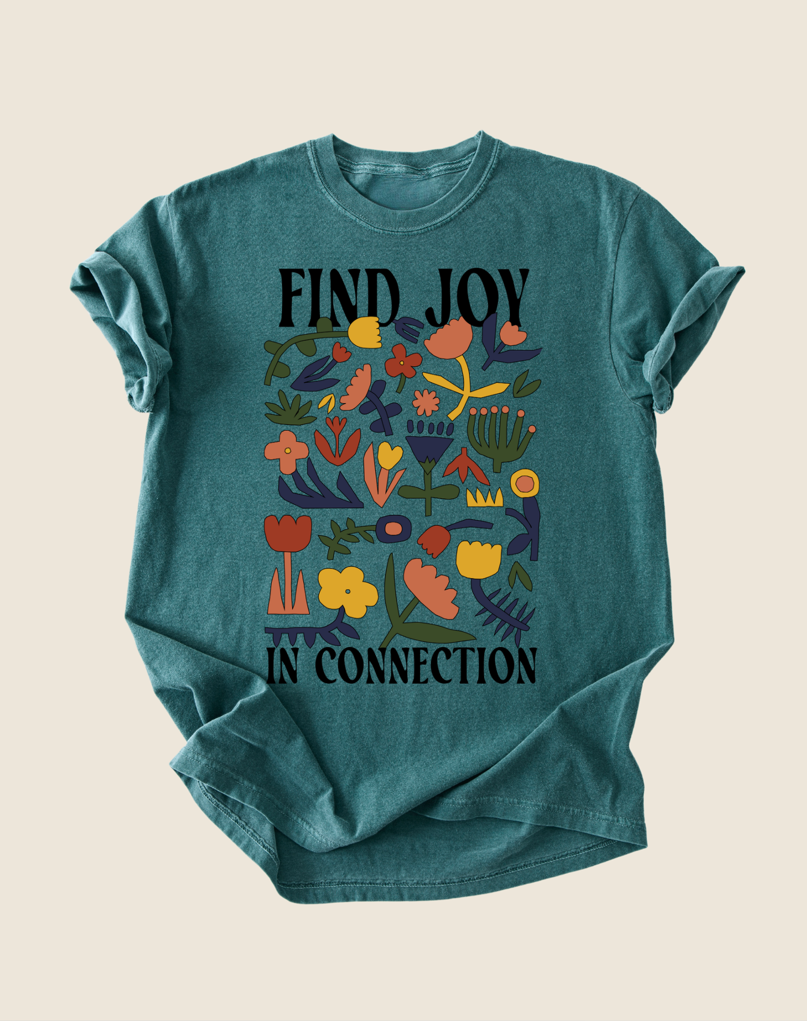 Teal t-shirt with colorful floral design and text 'Find Joy in Connection' on a beige background