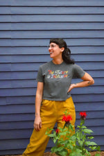 Person wearing a gray t-shirt with colorful text in front of a blue wall