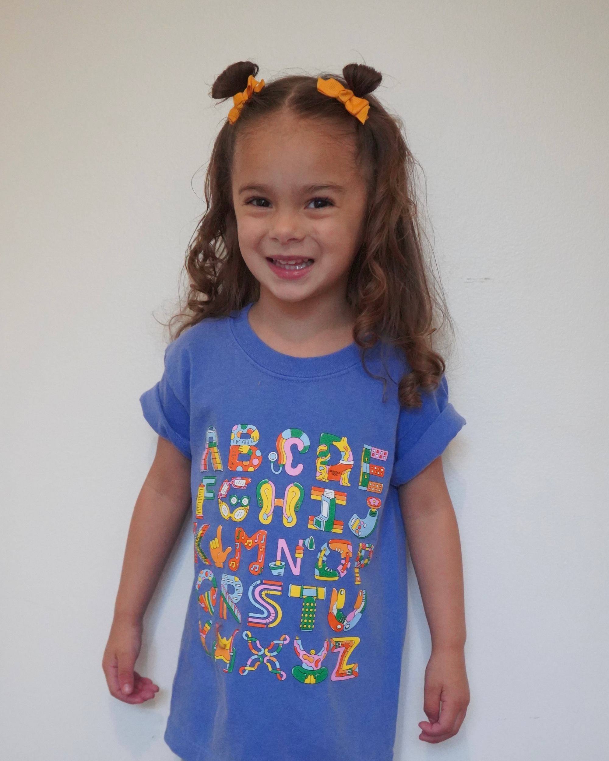 A child wearing a blue t-shirt with colorful text design.
