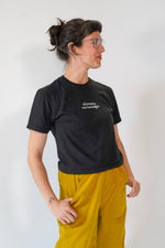 Person wearing a black t-shirt and yellow pants against a white background