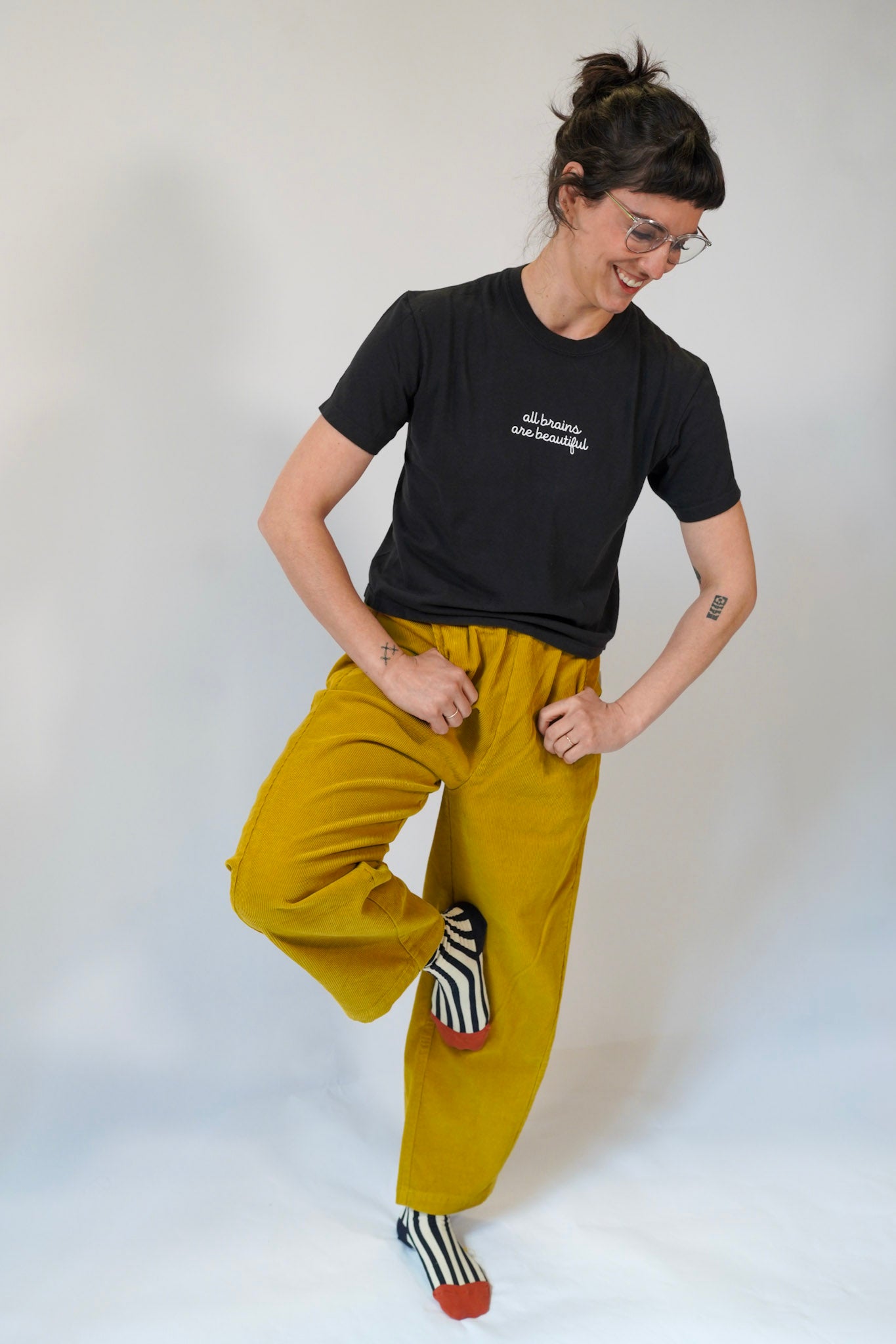 Person wearing a black t-shirt and mustard yellow pants on a white background