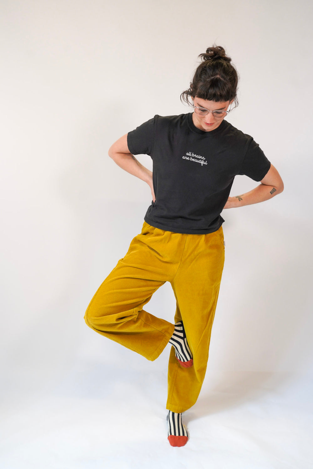 Person wearing a black t-shirt and mustard yellow pants on a white background