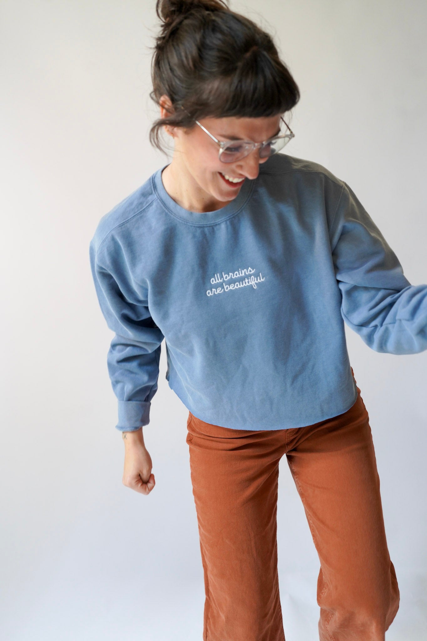 Person wearing a blue sweatshirt with text and brown pants on a plain background