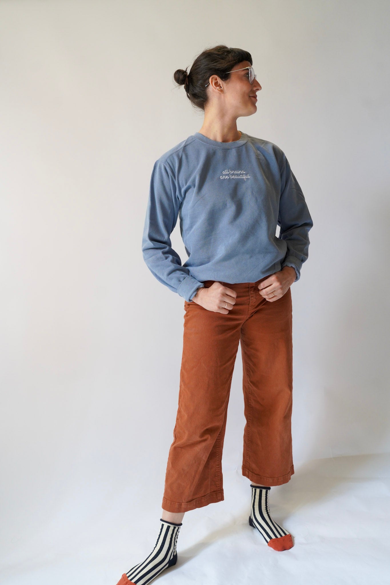 Person wearing a blue sweatshirt and brown pants against a white background