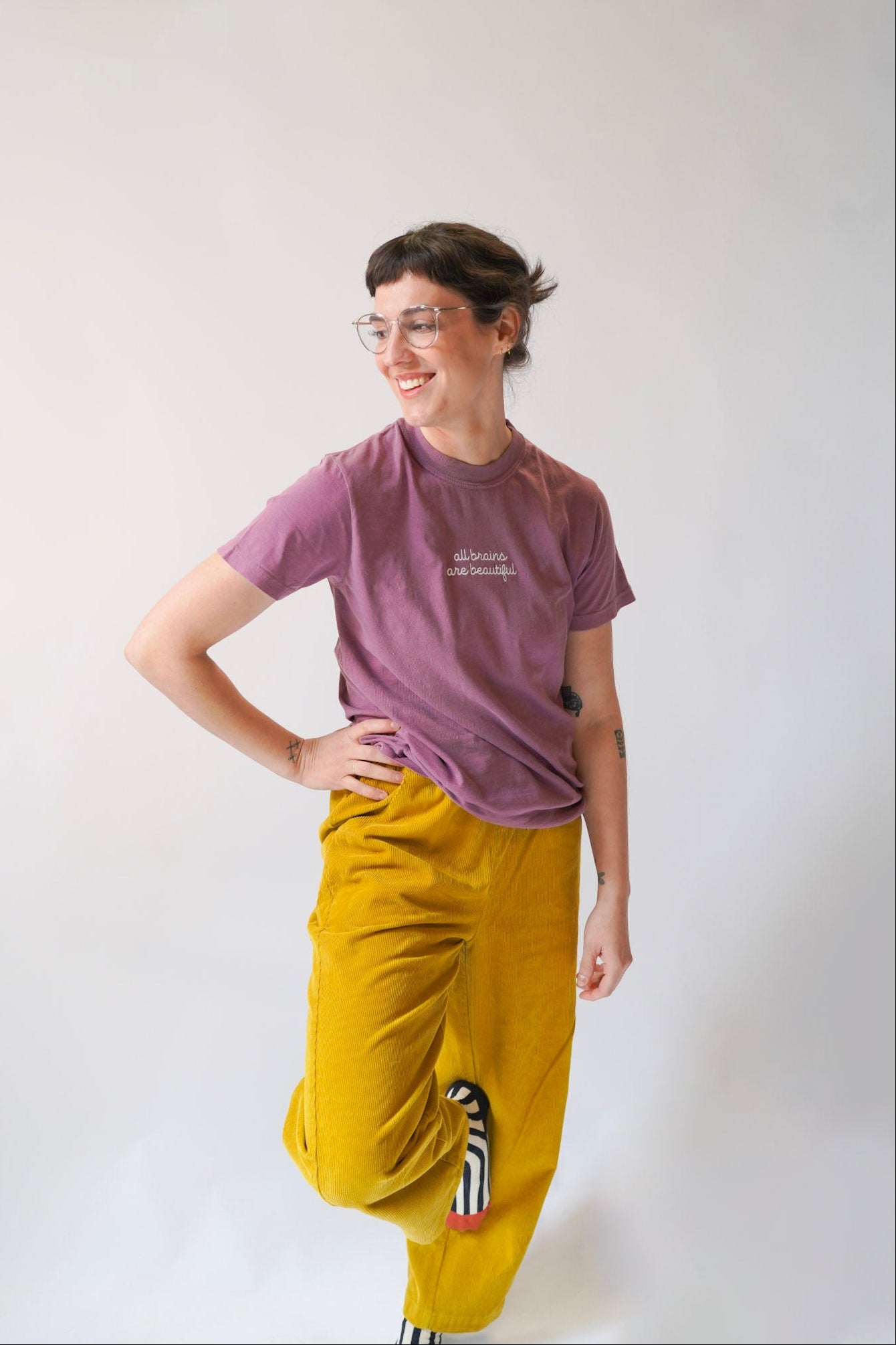 Person wearing a purple t-shirt and yellow pants with a white background