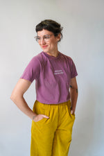 Person wearing a purple t-shirt and yellow pants against a white background