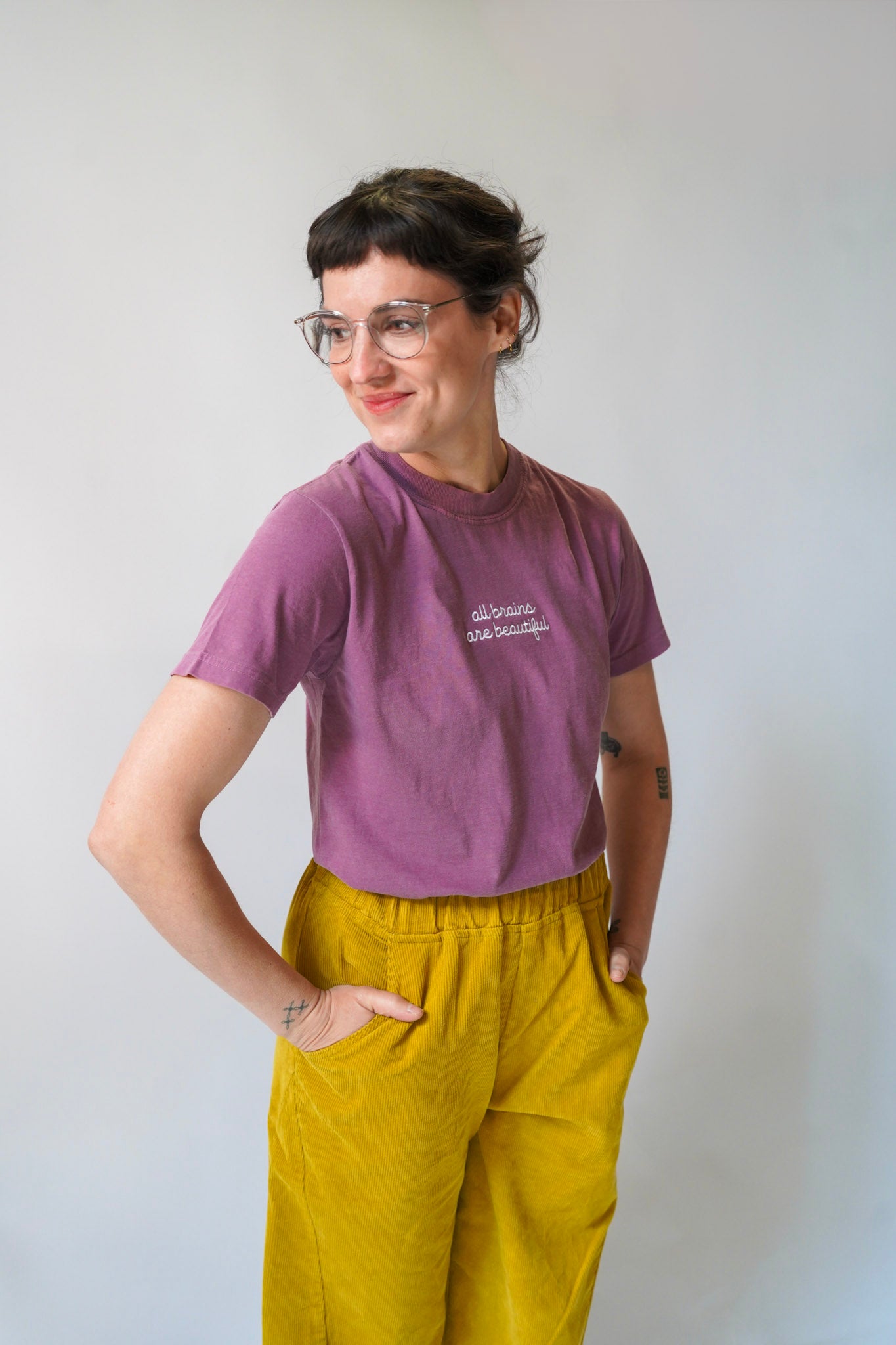 Person wearing a purple t-shirt and yellow pants against a white background