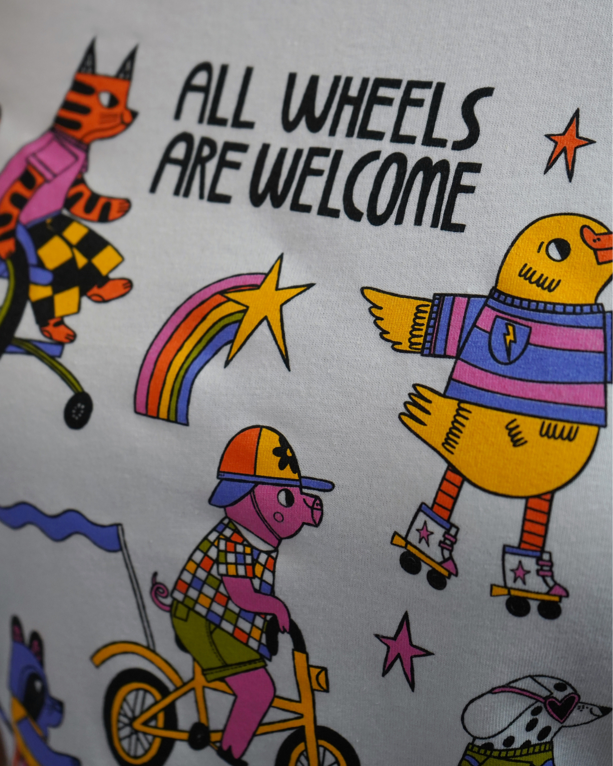 Cartoon characters with text 'All Wheels Are Welcome' on a colorful background