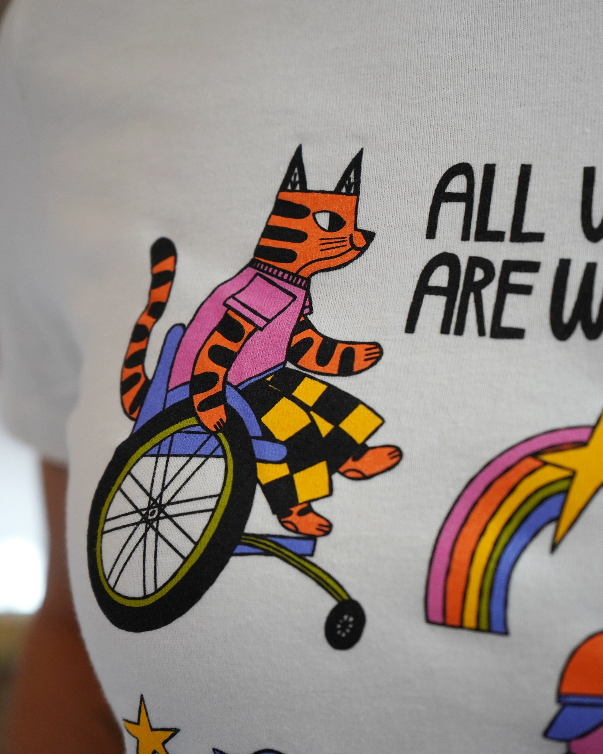 T-shirt with a tiger riding a unicycle, rainbow, and text on a white background