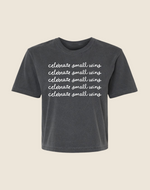 A gray t-shirt with the text 'celebrate small wins' printed in a repeating pattern across the front.