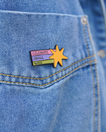 Pin with 'Celebrate Small Wins' text on a denim jacket