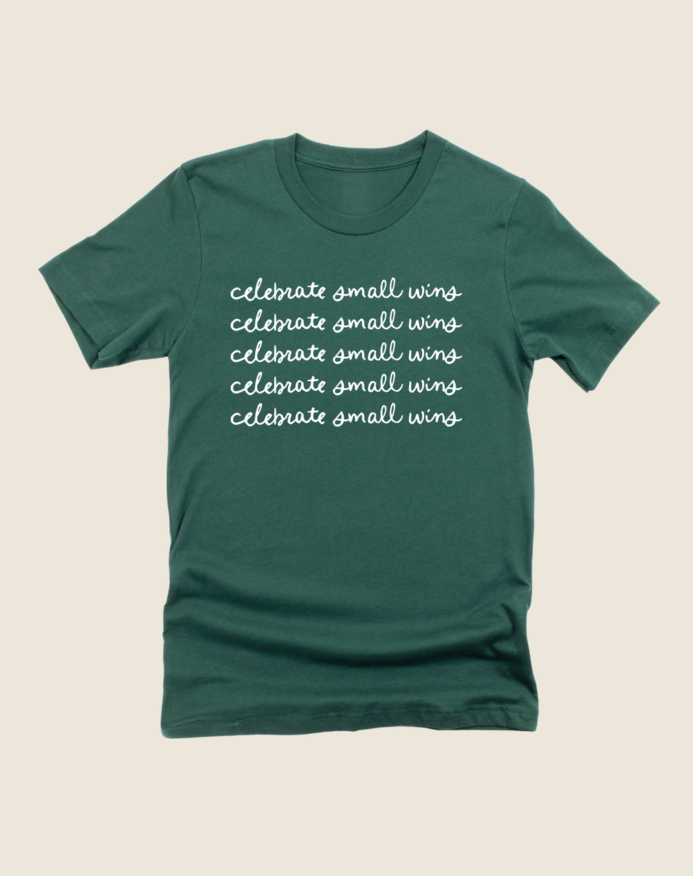 Green t-shirt with 'celebrate small wins' text on a beige background