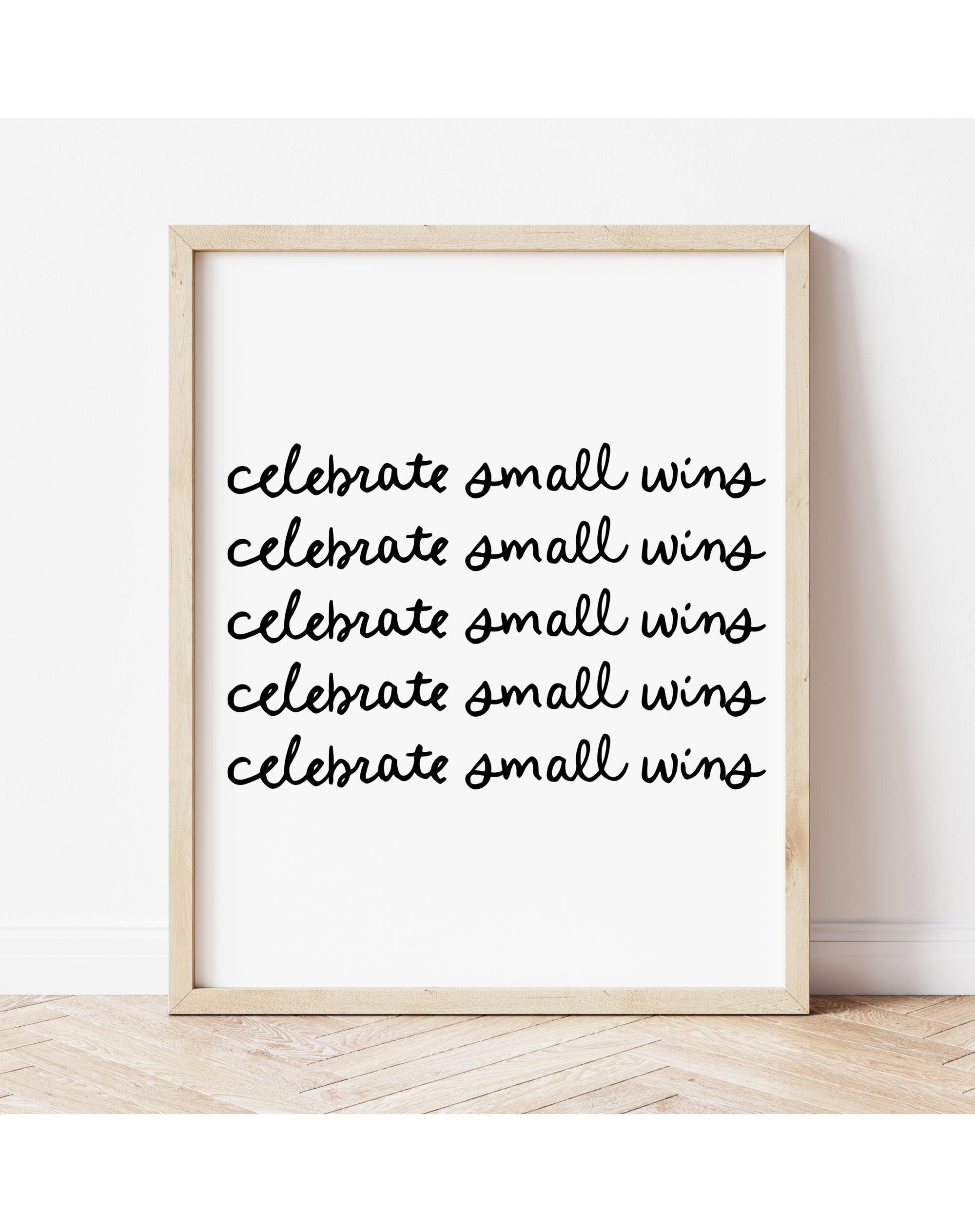 A illustrated art print with text 'celebrate small wins' displayed in a wooden frame.