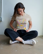 A person wearing a beige t-shirt with the text 'CONNECT THROUGH PLAY' and a colorful illustration of various playful icons.