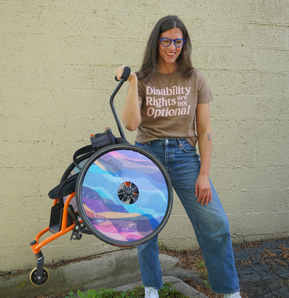 Person with a wheelchair featuring a colorful wheel design against a beige wall.