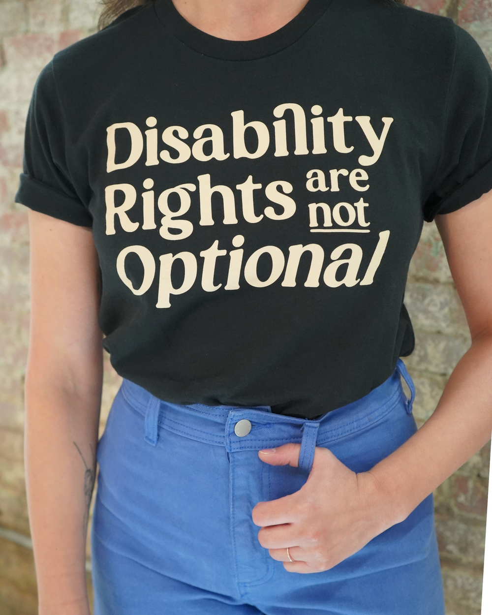 A person wearing a black t-shirt with 'Disability Rights Are Not Optional' printed in yellow text.