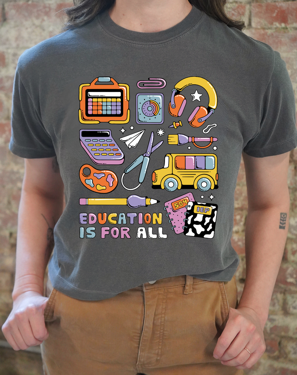 Person wearing a gray t-shirt with colorful educational graphics and 'Education is for All' text.