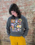 Person wearing a gray sweatshirt with colorful graphics and 'Education is for All' text against a brick wall.