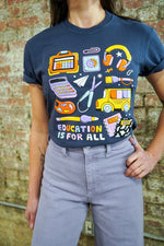 Person wearing a t-shirt with educational graphics and 'Education is for All' text against a brick wall.