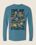 Blue long-sleeve shirt with floral design and text 'Find Joy In Connection' on a beige background