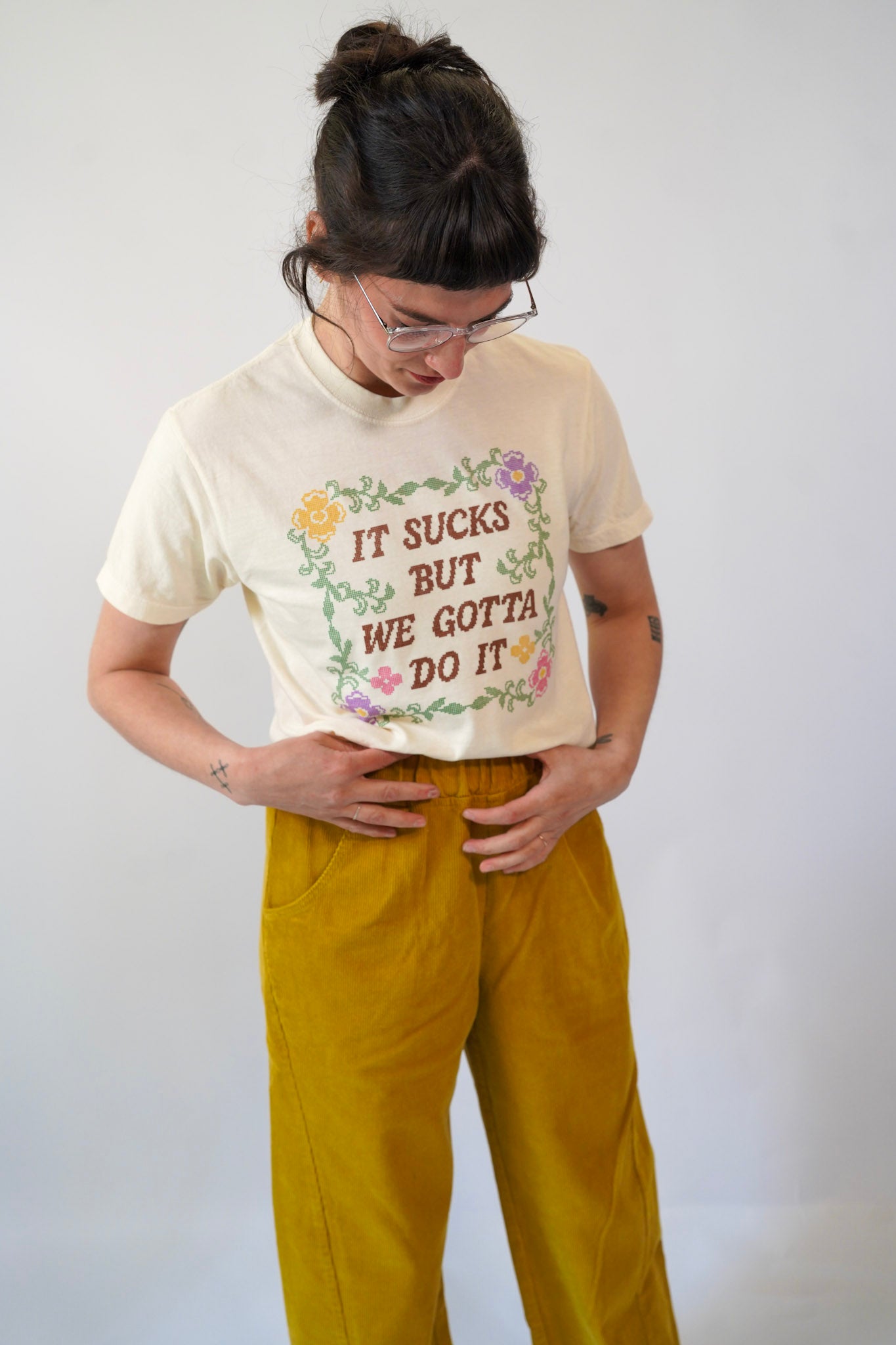 Person wearing a graphic t-shirt with text and floral design on a plain background