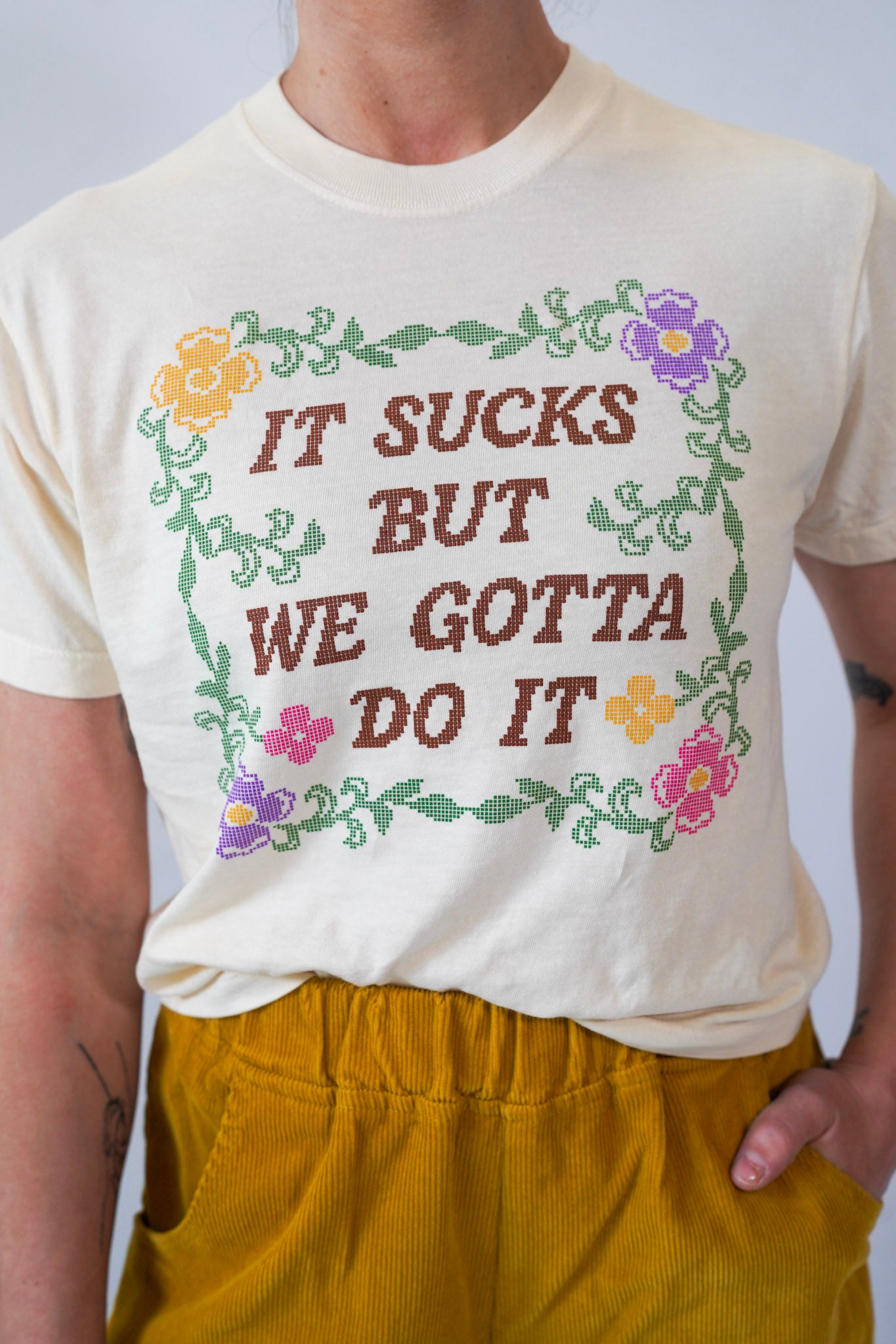 Person wearing a graphic t-shirt and mustard yellow pants on a plain background