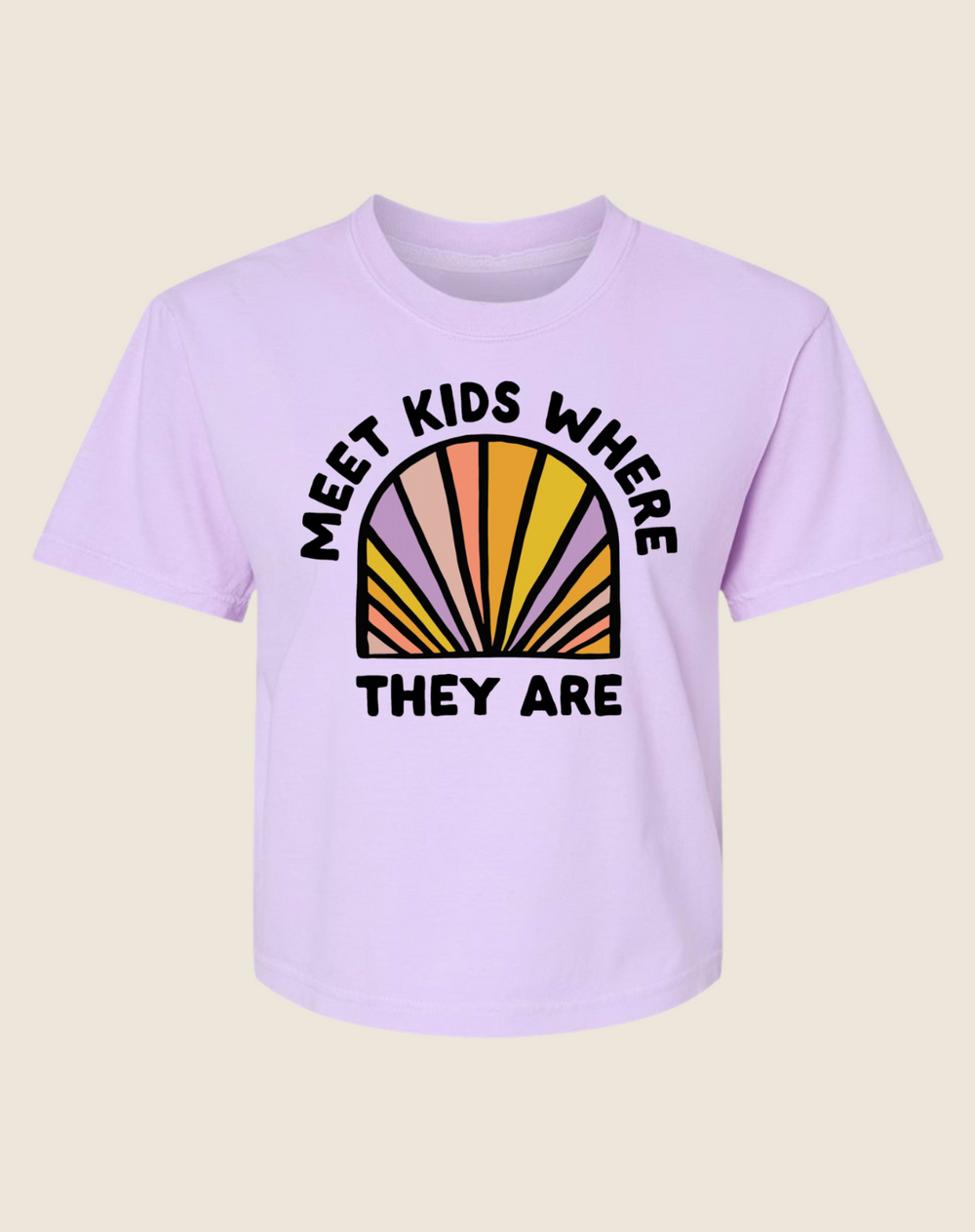 A pink crew neck t-shirt with the text 'MEET KIDS WHERE THEY ARE' and a multicolored semi-circle design behind the text.