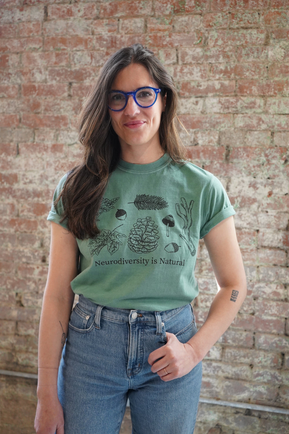 A person wearing a green t-shirt with an illustration and text related to neurodiversity.