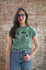 A person wearing a green t-shirt with an illustration and text related to neurodiversity.