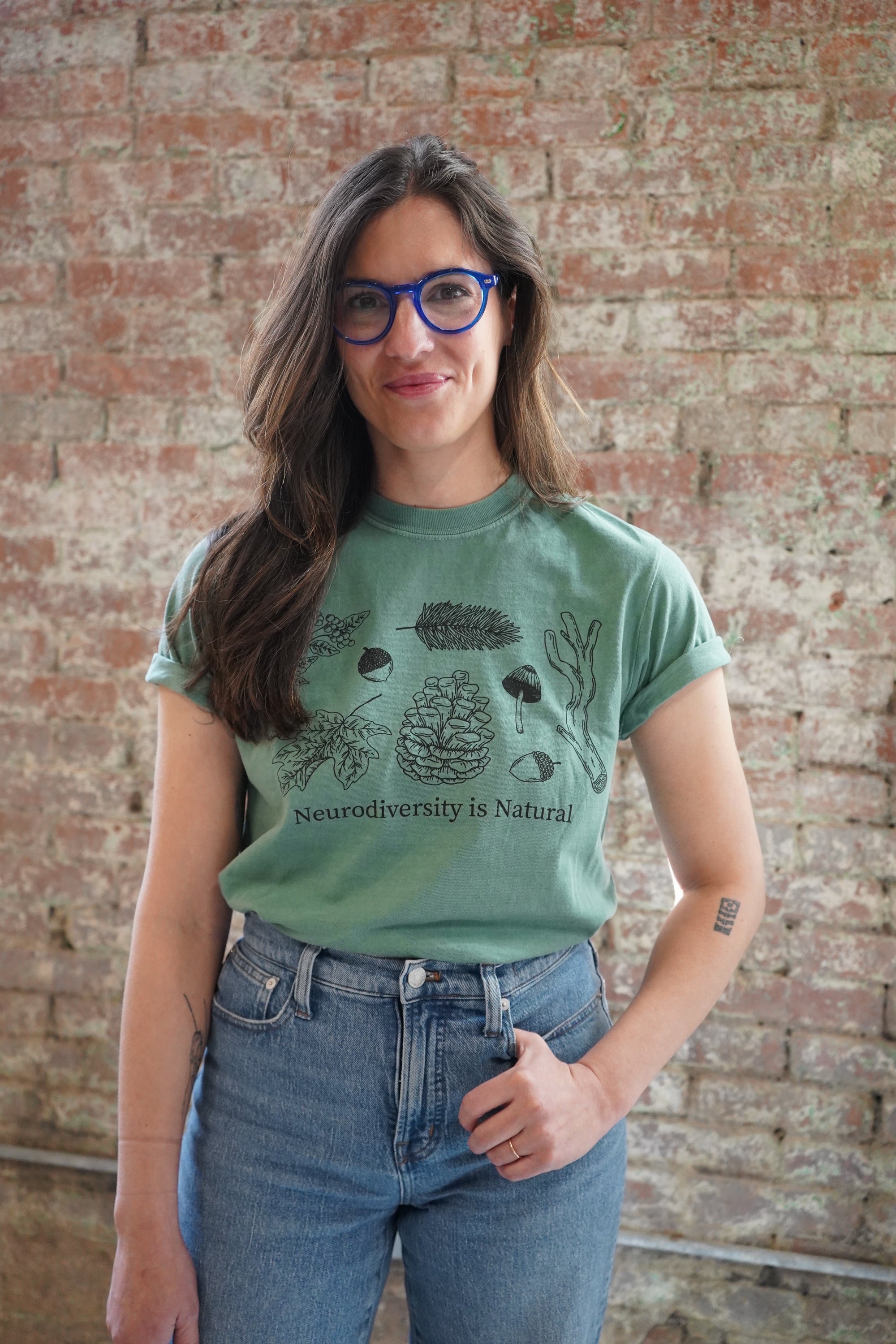 A person wearing a green t-shirt with an illustration and text related to neurodiversity.