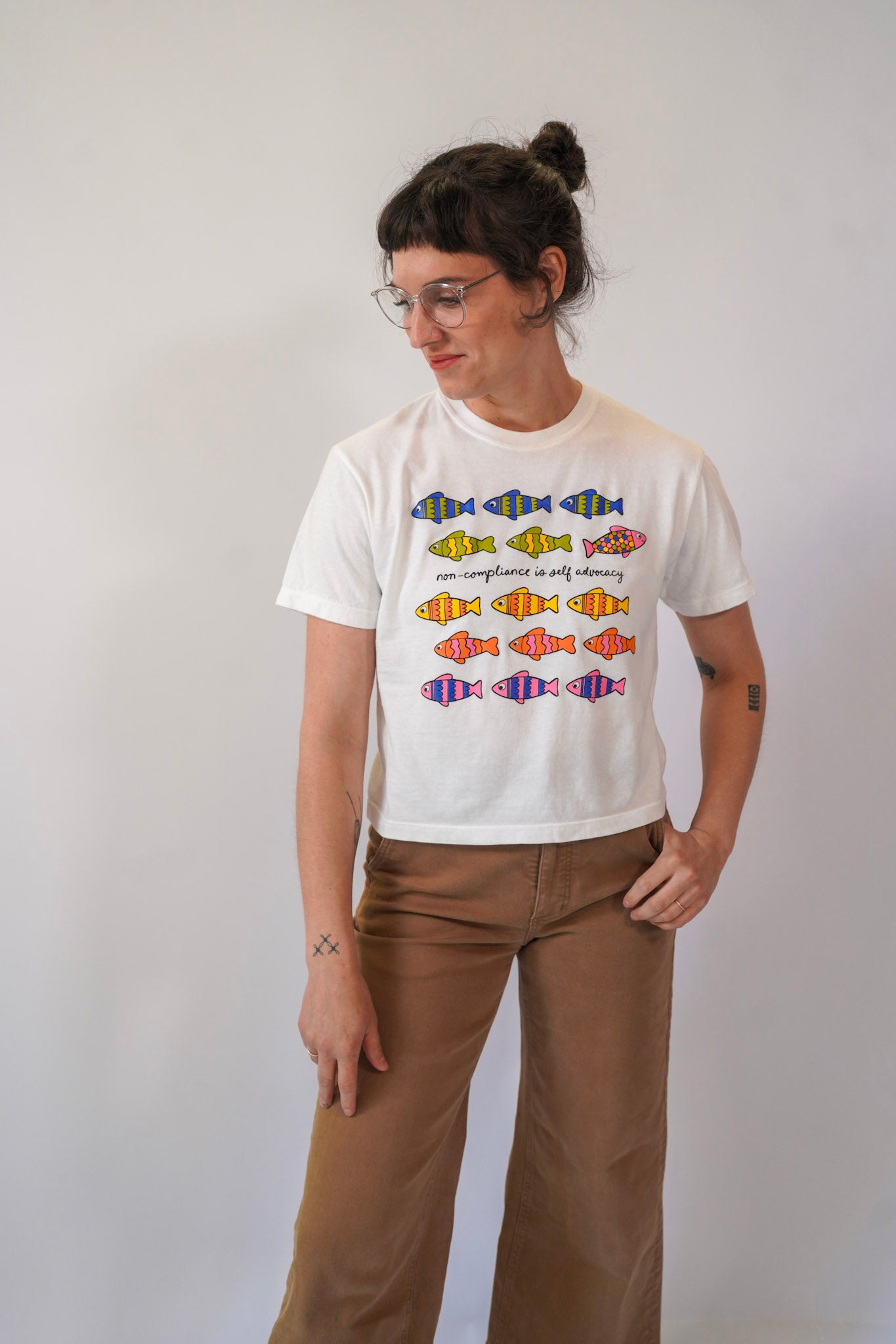 Person wearing a white t-shirt with colorful fish graphics on a plain background