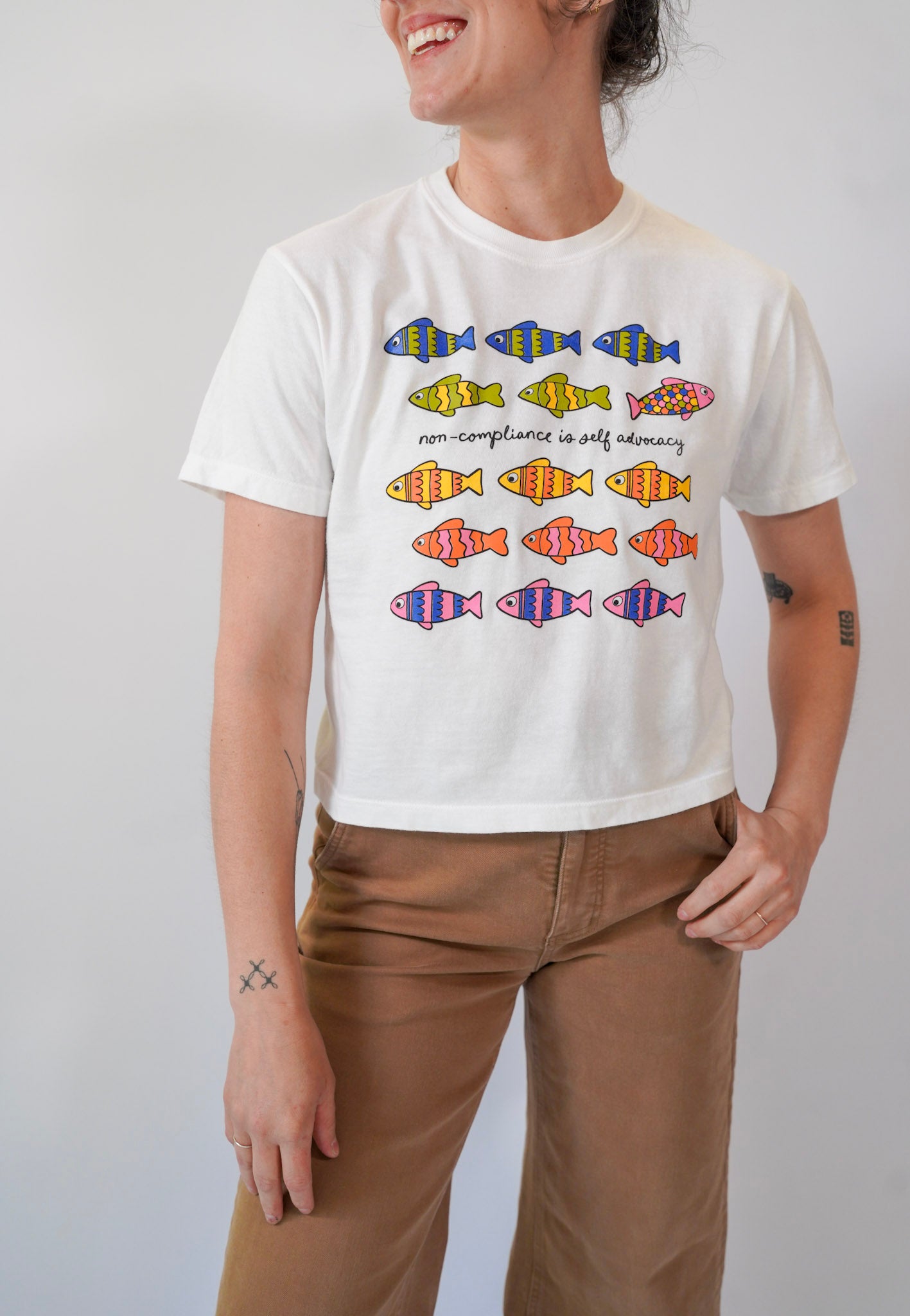 Person wearing a white t-shirt with colorful fish designs on a plain background