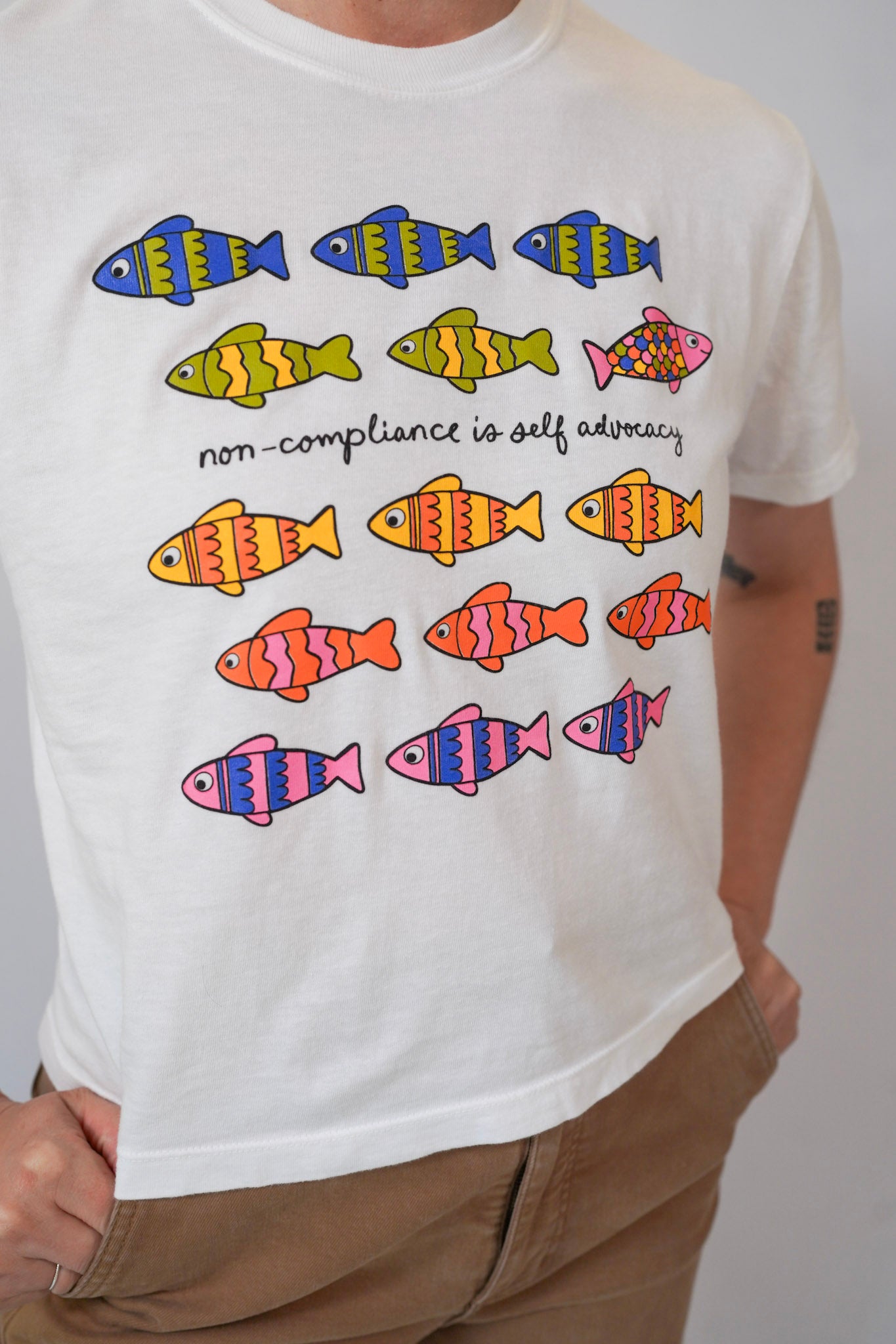 White t-shirt with colorful fish illustrations and text on a plain background