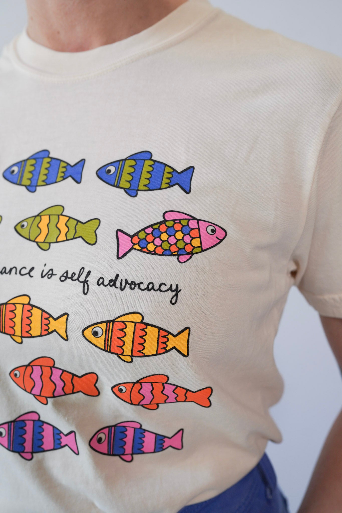 T-shirt with colorful fish illustrations and text on a plain background