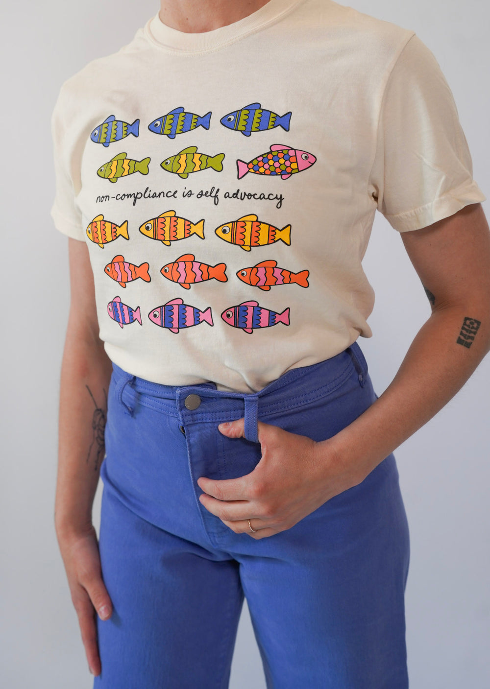 Person wearing a t-shirt with colorful fish graphics and text.