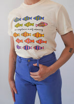 Person wearing a t-shirt with colorful fish graphics and text.