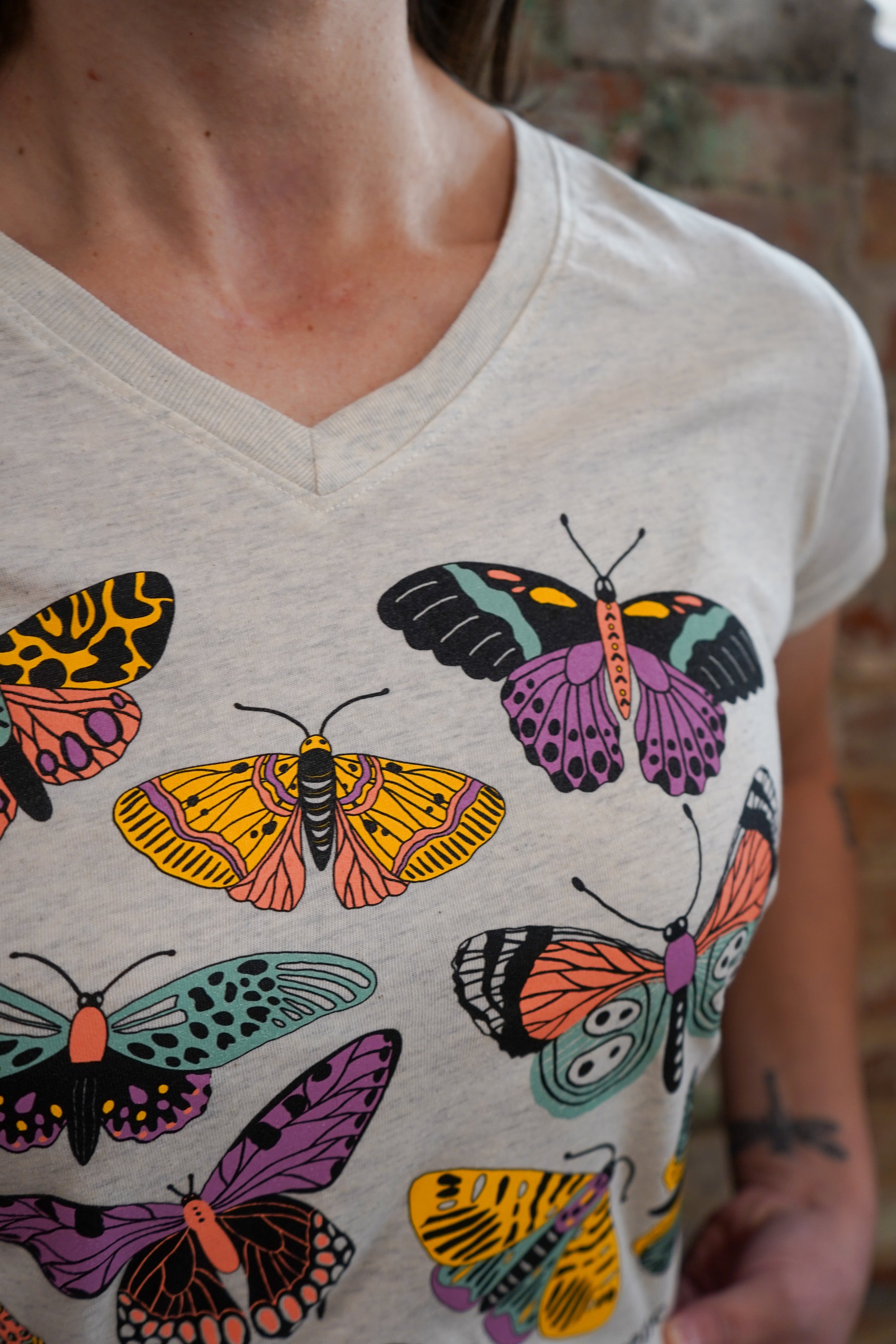 Person wearing a t-shirt with colorful butterfly designs.