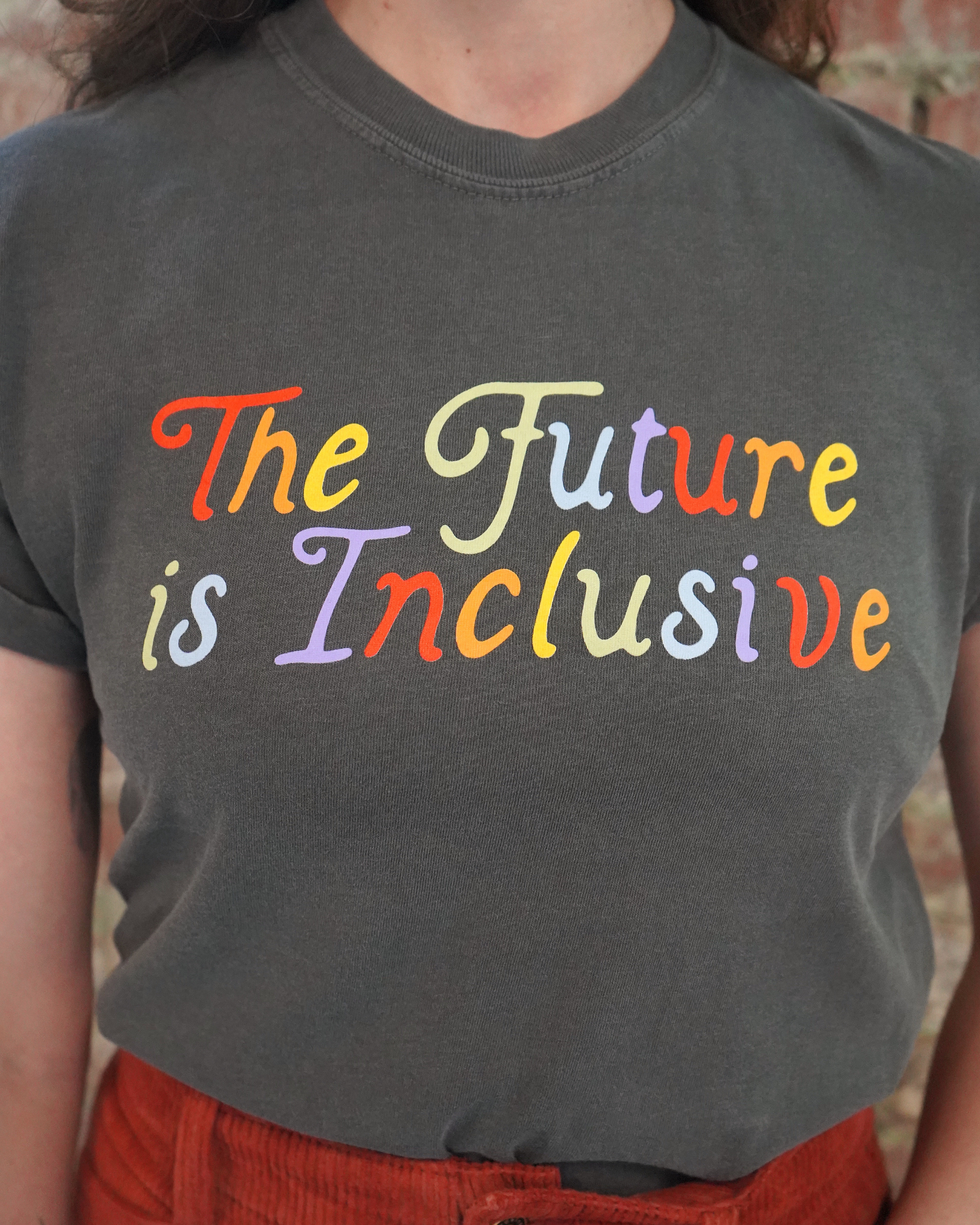 Person wearing a dark gray t-shirt with 'The Future is Inclusive' in colorful letters.
